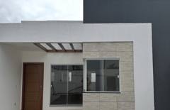 Fachada com porta de madeira, janelas amplas e cobertura com vigas aparentes.