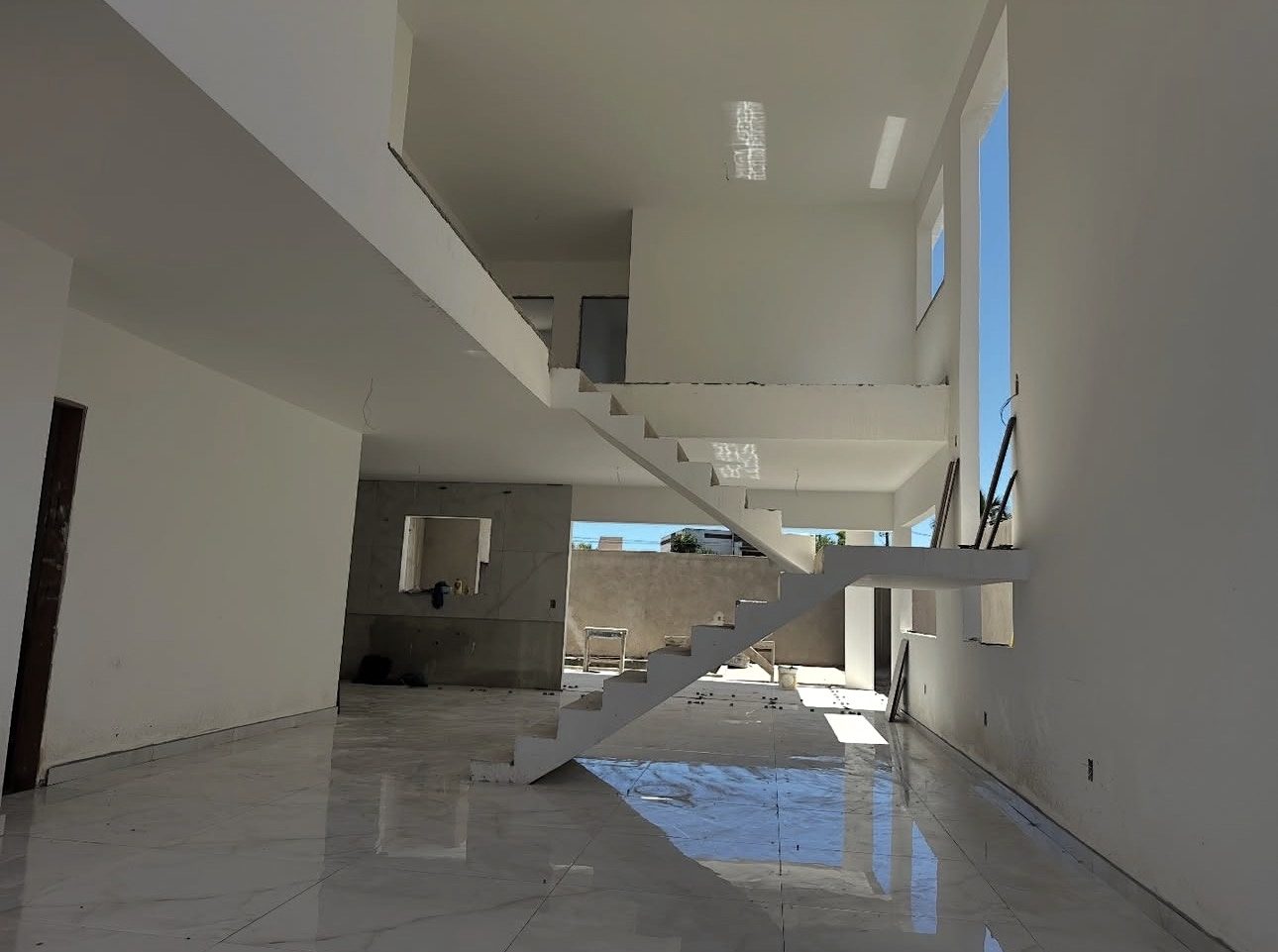 Sala com pé-direito duplo e escada, em obra