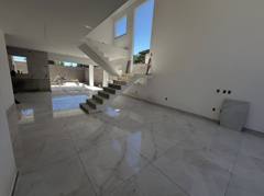 Escada suspensa em sala ampla com piso claro e janelas altas.